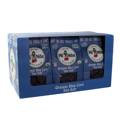 A blue box contains three bags of Mi Niña Tortilla Organic Blue Corn Sea Salt Tortilla Chip - 9 Pack / 12 oz, visible through a clear front window.