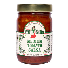 A 6 pack of Mi Niña Tortilla Medium Tomato Salsa (12.8 oz each) in glass jars with gold lids, featuring labels with a woman in traditional dress, green designs, and “Made with Organic Tomatoes.”.