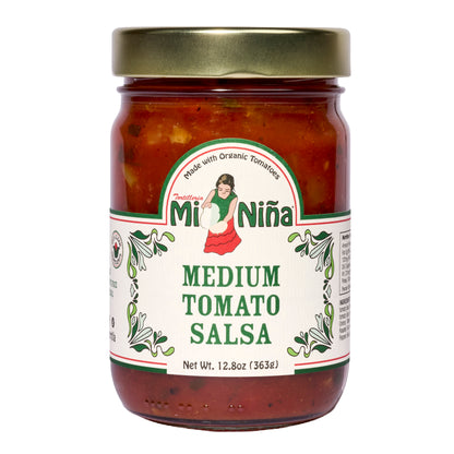 A 6 pack of Mi Niña Tortilla Medium Tomato Salsa (12.8 oz each) in glass jars with gold lids, featuring labels with a woman in traditional dress, green designs, and “Made with Organic Tomatoes.”.