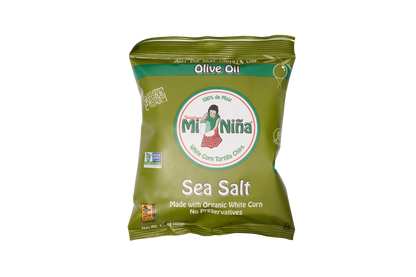 A green bag of Mi Niña Tortilla Sea Salt Made with Olive Oil chips (24 Pack / 1.5 oz), crafted from organic white corn and free from preservatives for a deliciously crisp texture. The package features a cartoon woman and displays various certifications.