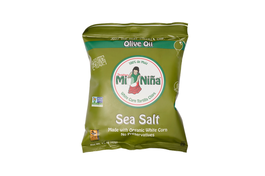 A green bag of Mi Niña Tortilla Sea Salt Made with Olive Oil chips (24 Pack / 1.5 oz), crafted from organic white corn and free from preservatives for a deliciously crisp texture. The package features a cartoon woman and displays various certifications.