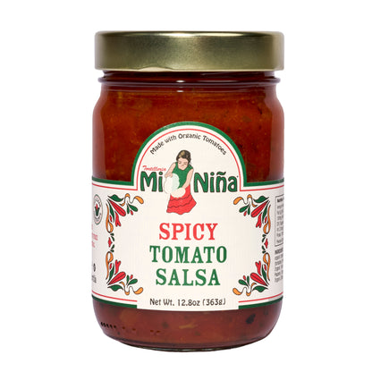 A 12.8 oz glass jar of Mi Niña Tortilla Spicy Tomato Salsa, featuring a gold lid and white label with a woman holding tomatoes and red-green patterns. Made with organic tomatoes. Sold in a convenient 6 pack.